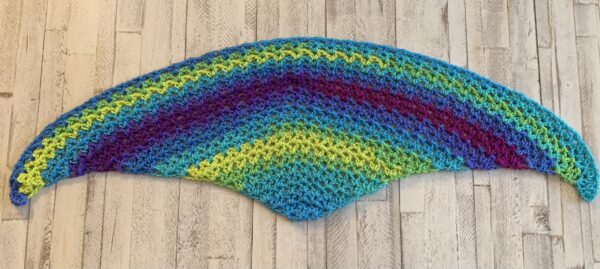 crochet shawl in the color tetra on a white board background