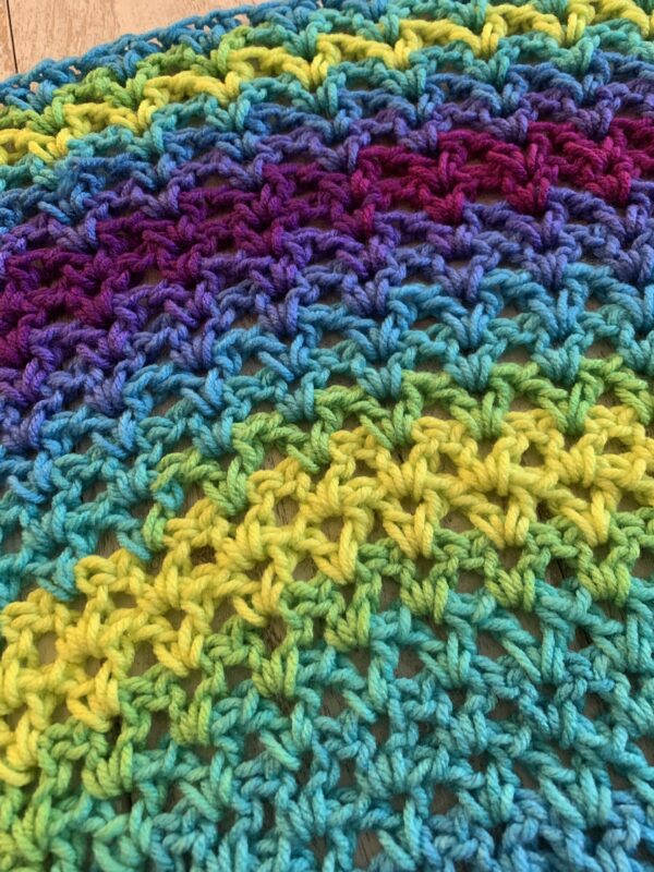 crochet shawl in the color tetra on a white board background