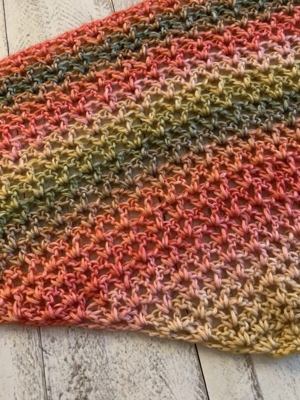 crochet shawl in the color strawberry patch on a white board background